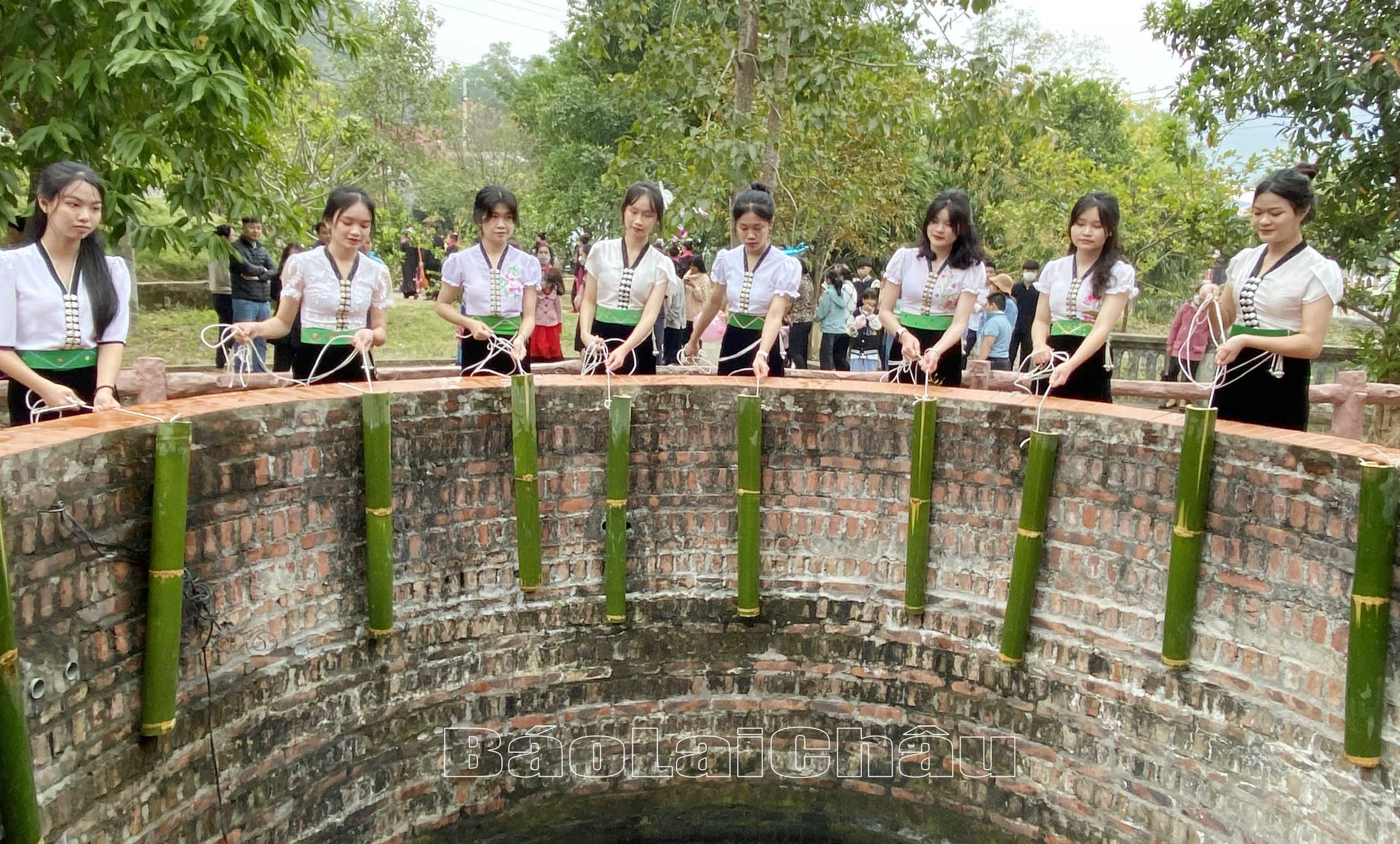 Các thiếu nữ người Thái dùng ống tre múc nước từ mó nước Nàng Han.